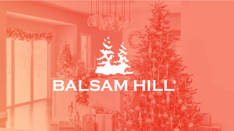 Balsam Hill logo placed on top of image of Christmas tree and Christmas decorations.