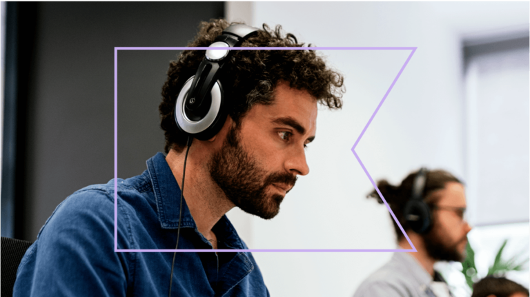 Profile view of person with headphones, with another person wearing headphones in the distance